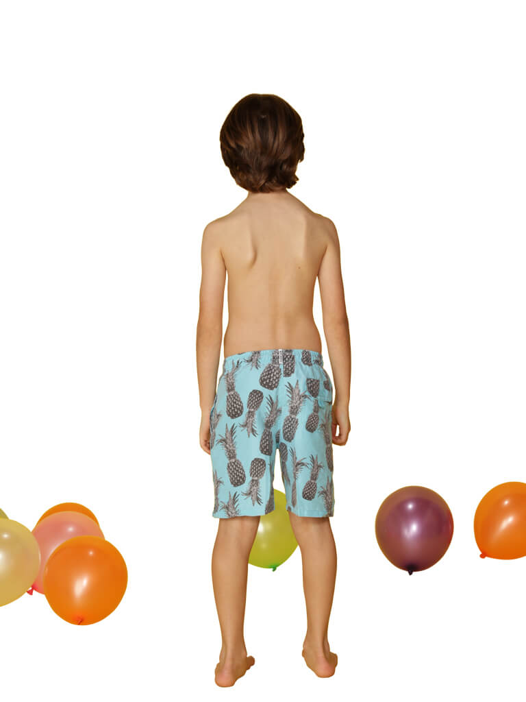 Boy's swim trunks printed in a spray of pineapples, back view