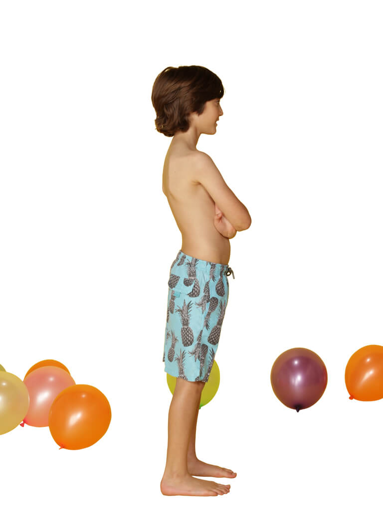 Boy's swim trunks printed in a spray of pineapples, side view